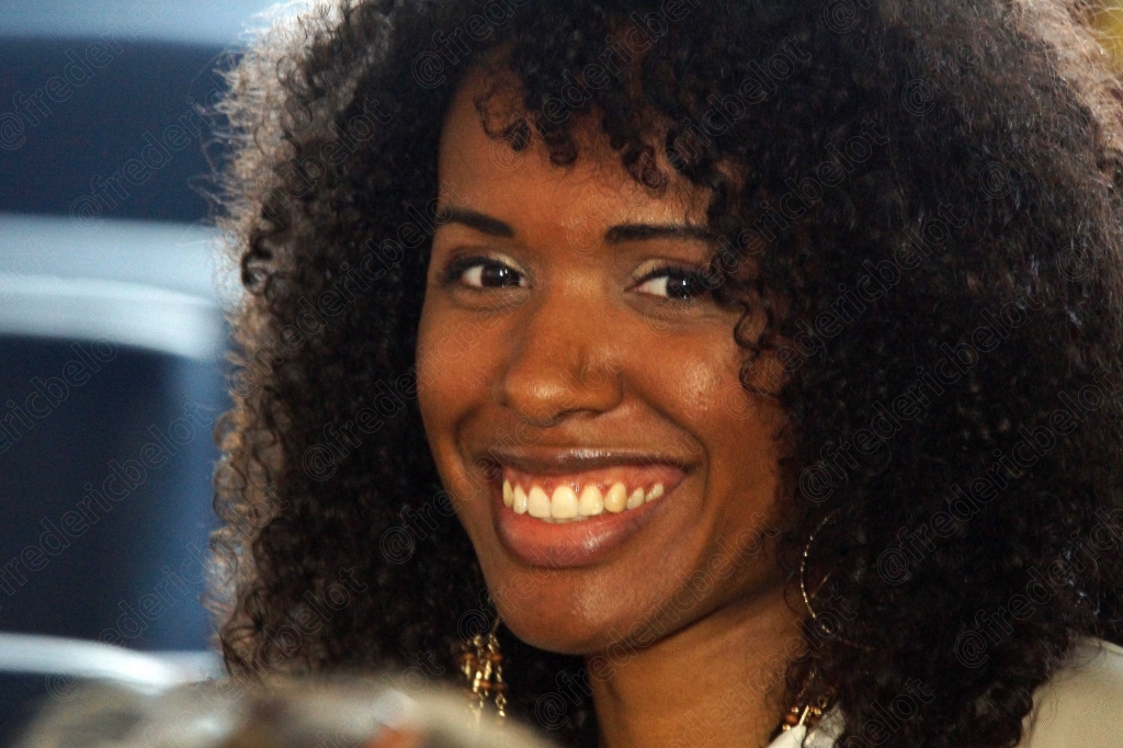 Femme aux cheveux bouclés souriant largement, gros plan