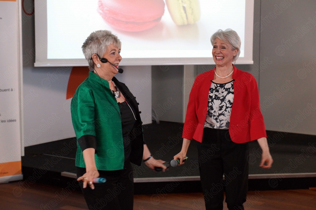 Deux femmes en veste verte et rouge, écran affichant des macarons