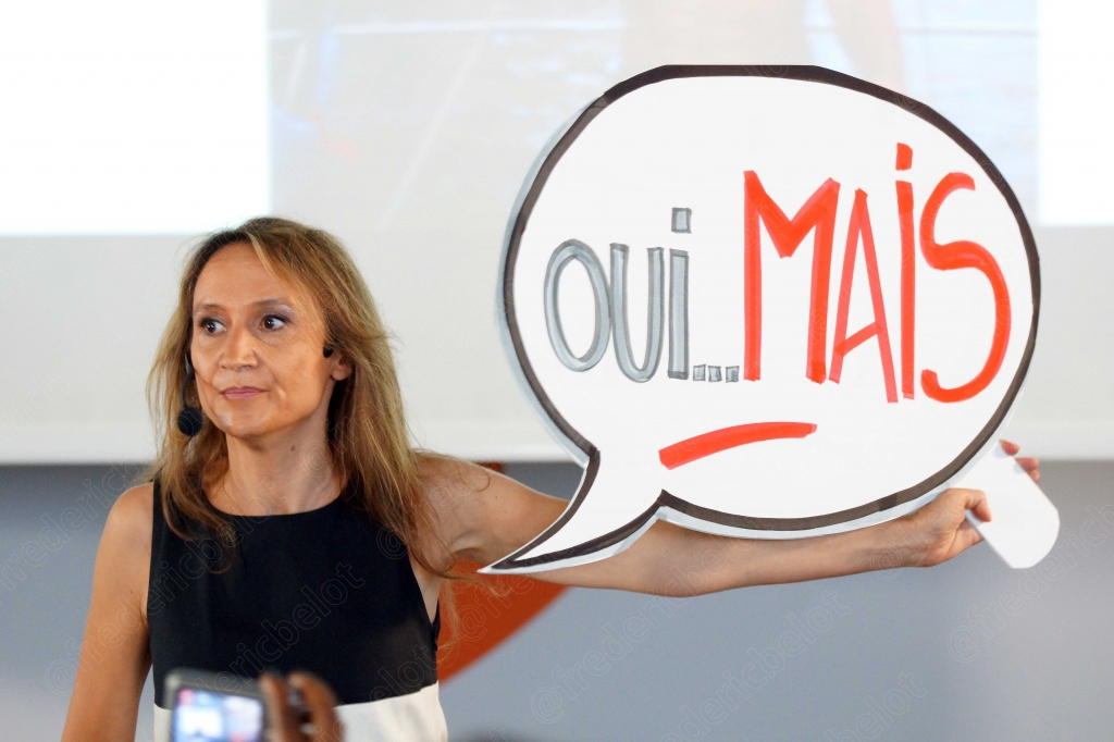 Femme blonde tenant une pancarte manuscrite « oui... MAIS »