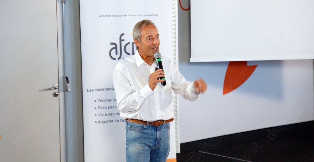 Homme aux cheveux gris parlant au micro devant le logo afcp