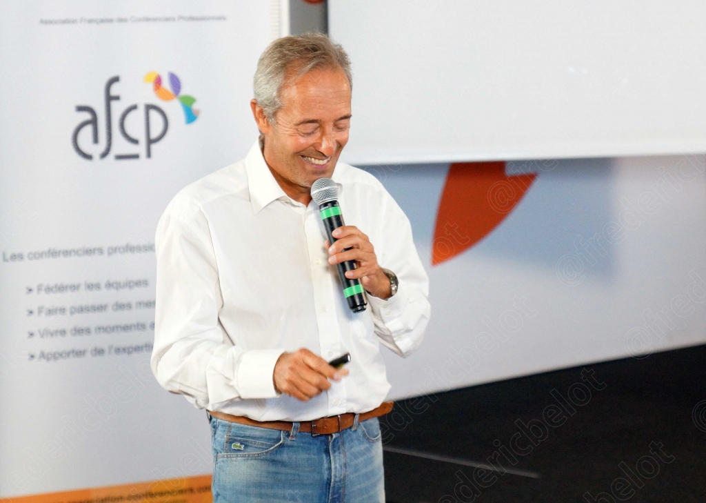 Homme aux cheveux gris parlant au micro devant le logo afcp