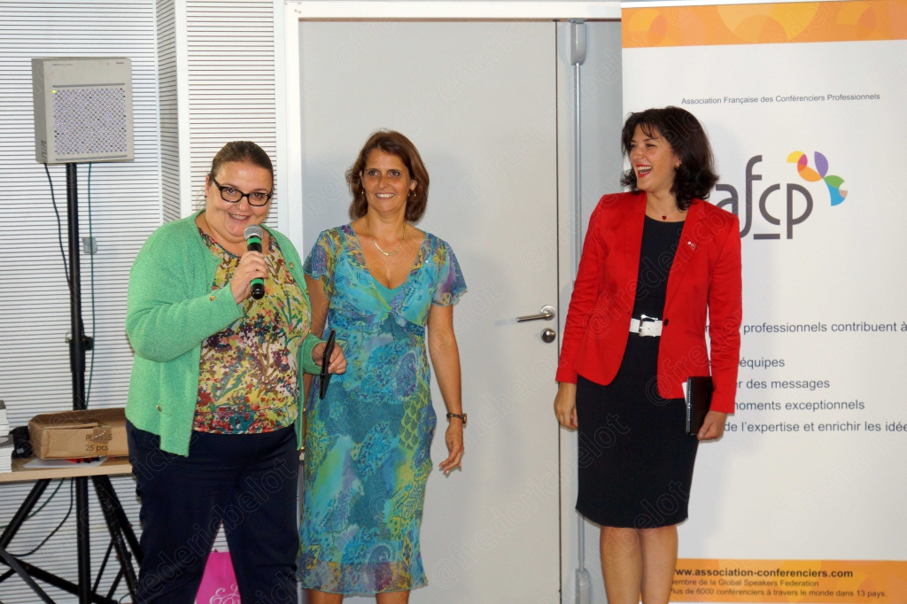 Trois femmes souriantes sur scène, dont une au micro, devant le logo afcp