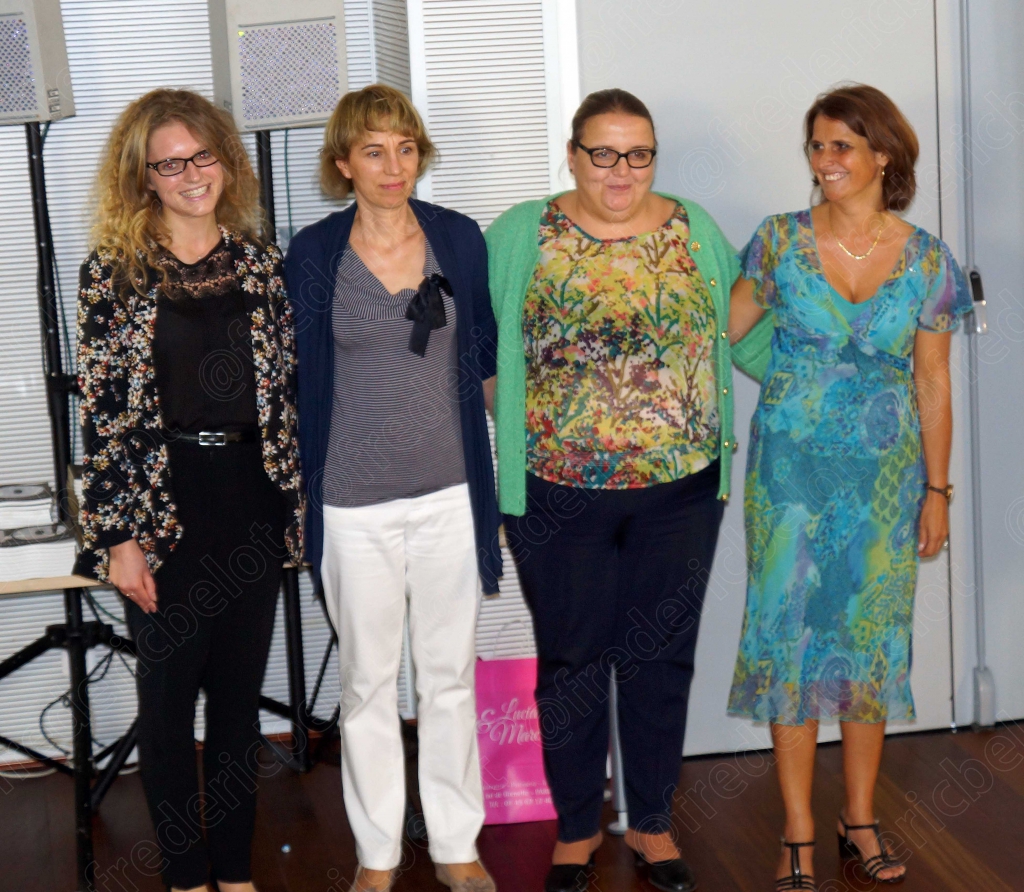 Quatre femmes posant côte à côte, souriantes, sacs cadeaux en main
