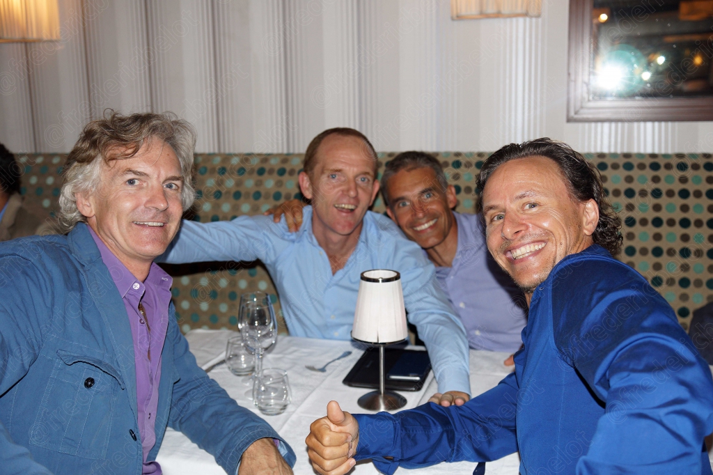 Trois hommes complices lèvent le pouce et prennent la pose autour d'une table.