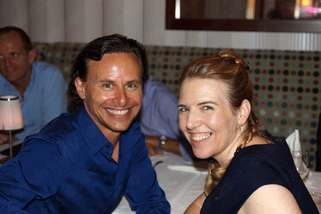 Un homme et une femme souriants, accoudés à la table, pendant le dîner.