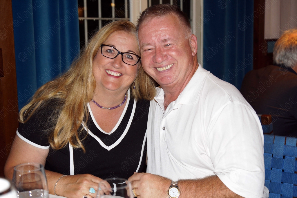 Un couple souriant trinque avec des verres à cocktail.