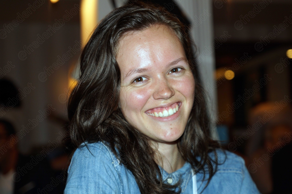 Portrait souriant d'une jeune femme aux cheveux bruns, à table.