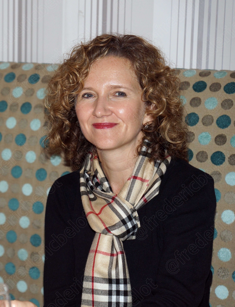 Portrait d'une femme aux cheveux bouclés, écharpe à motifs, souriante.
