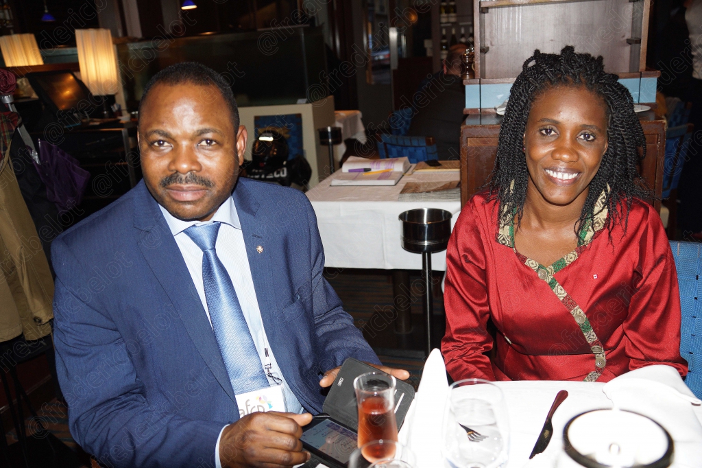 Un homme en costume et une femme posent souriants à table.