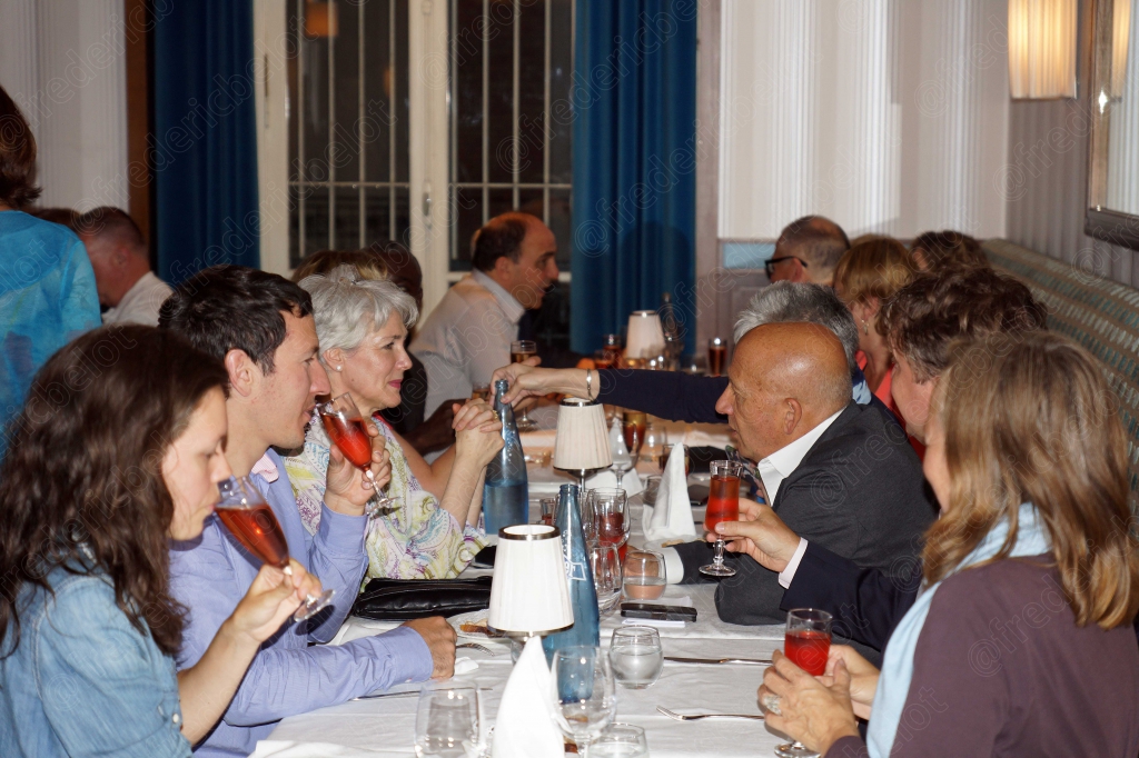 Une tablée de convives trinque ensemble dans une ambiance conviviale.