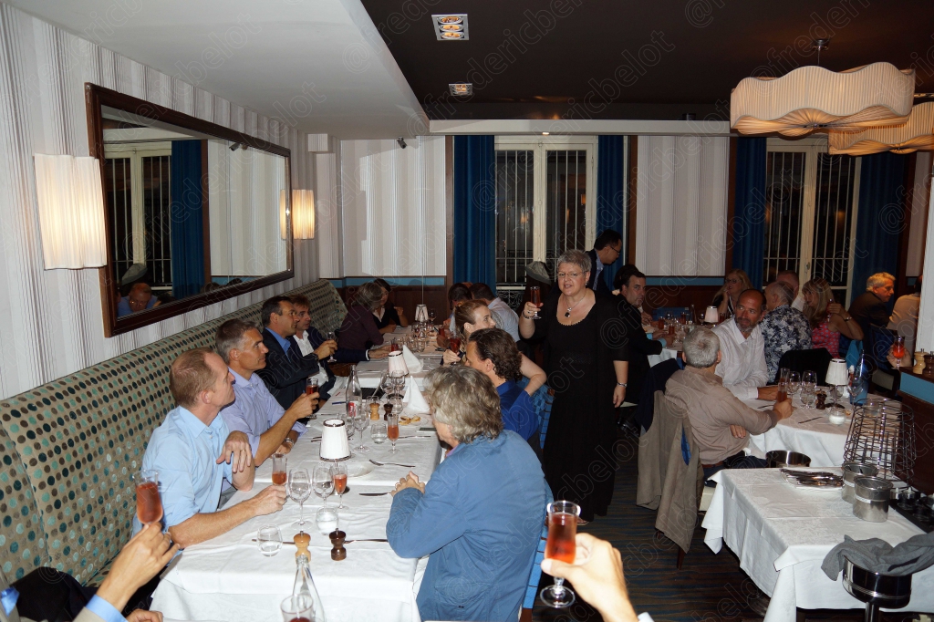 Vue d'ensemble de la salle du restaurant, plusieurs tablées en pleine discussion.
