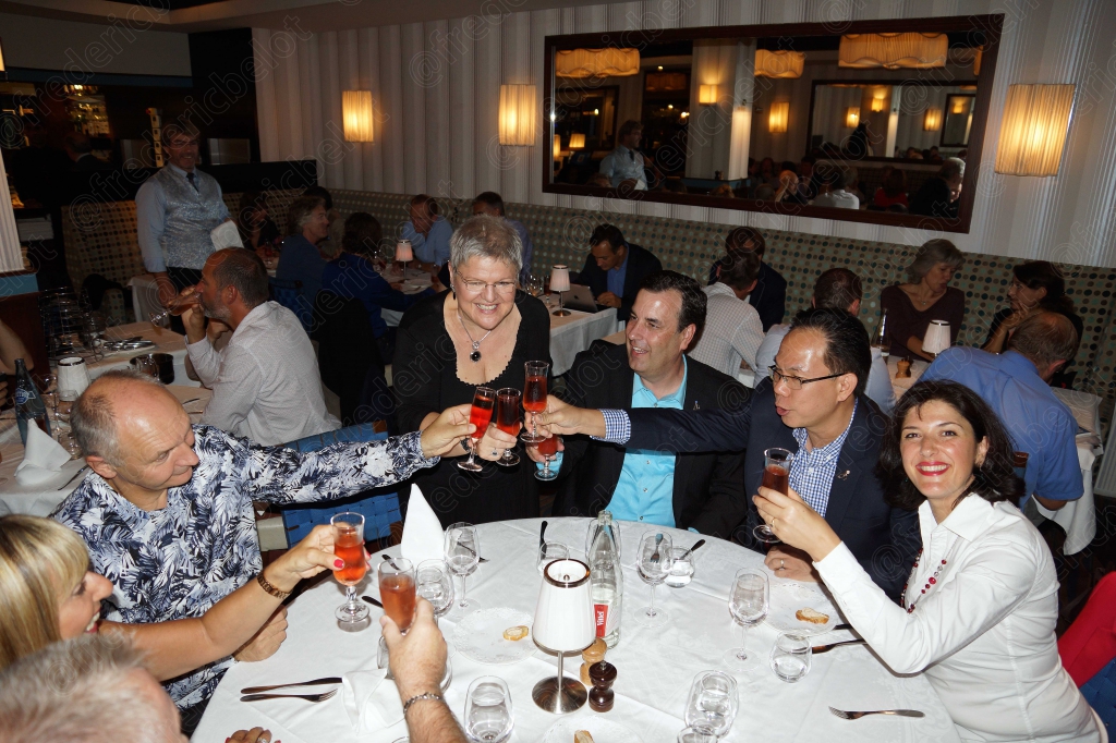 Un groupe de convives trinque autour d'une table ronde.