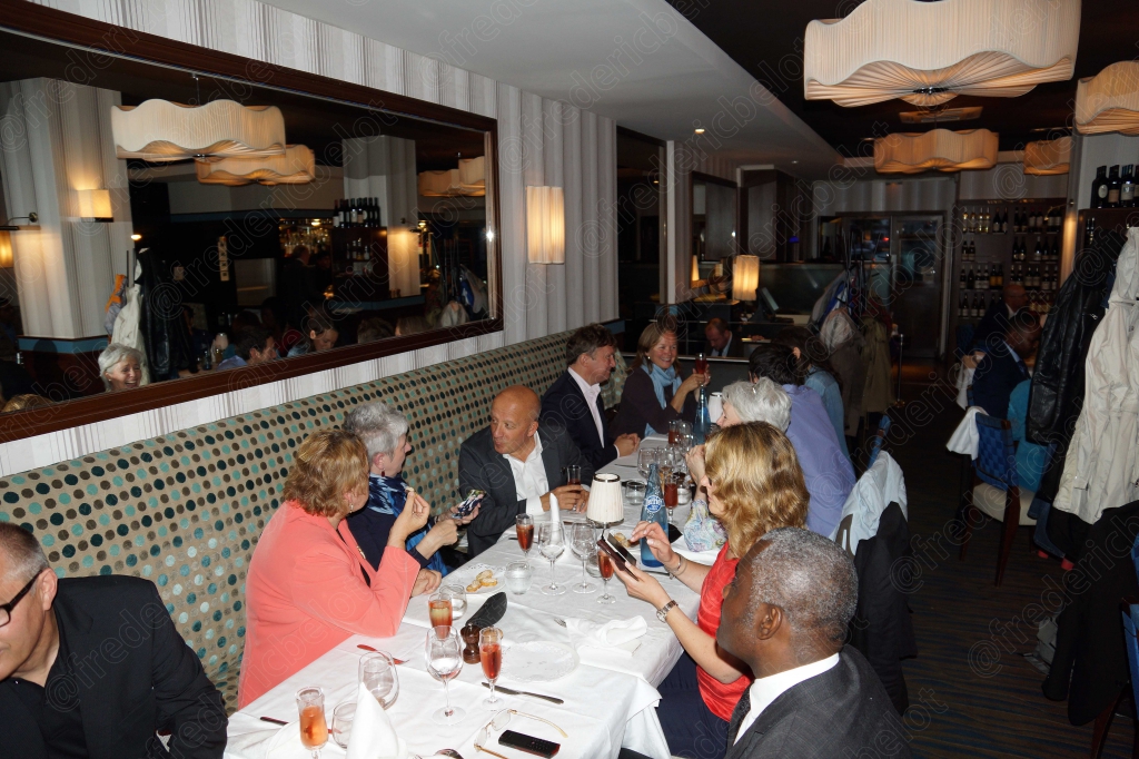 Vue sur la salle de restaurant depuis un angle, miroir reflétant l'ambiance de la soirée.