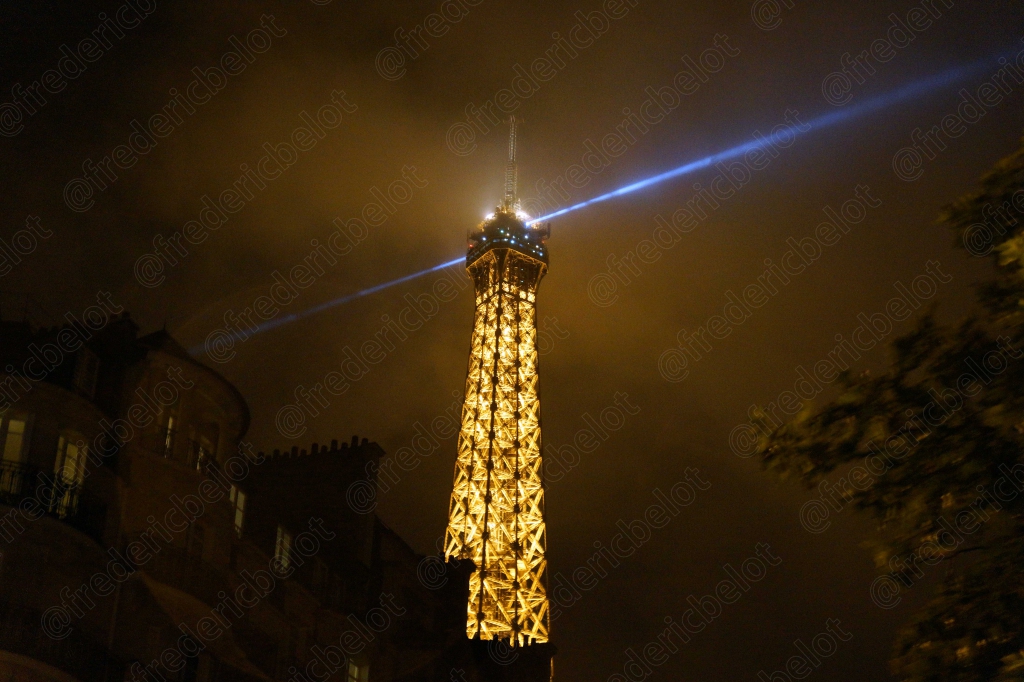 La tour Eiffel scintillante de nuit, vue depuis une terrasse en hauteur.