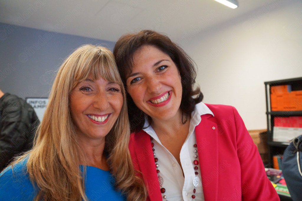 Deux femmes posent ensemble, l'une en veste rose, souriantes.