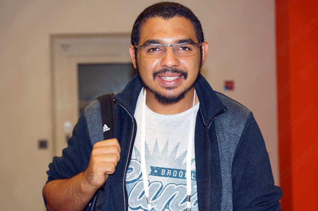Portrait souriant d'un jeune homme barbu, sac à dos sur l'épaule.