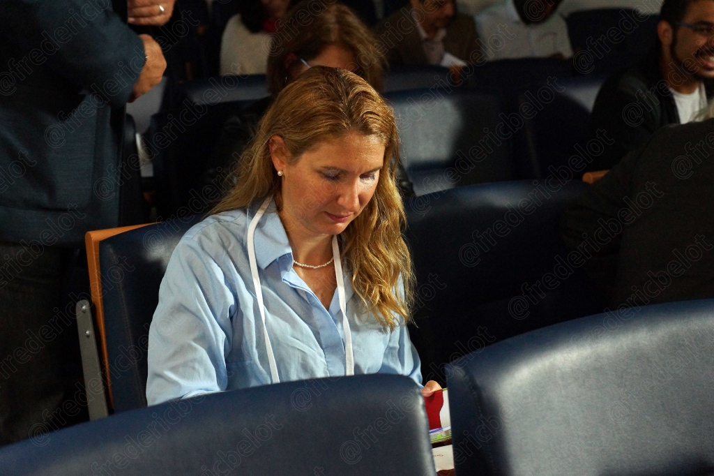 Une femme aux cheveux longs consulte ses notes, assise dans le public.
