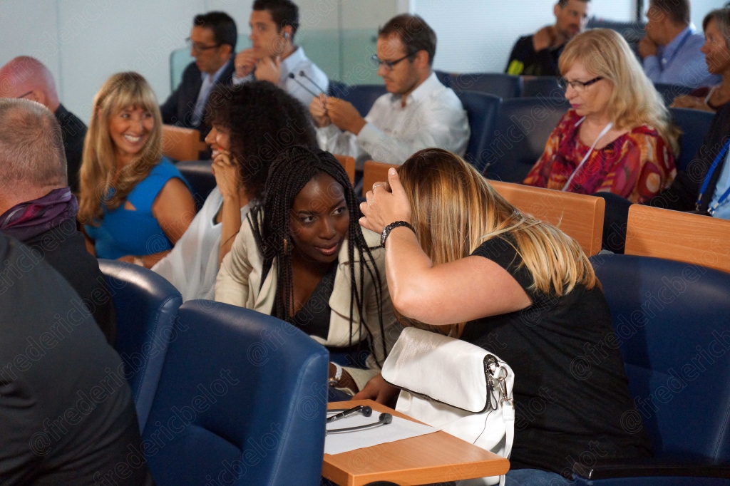 Un groupe de participantes assises dans le public échange en souriant.