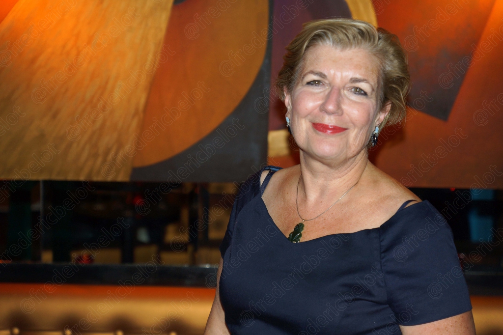 Portrait souriant d'une femme aux cheveux blonds, en robe bleu marine.