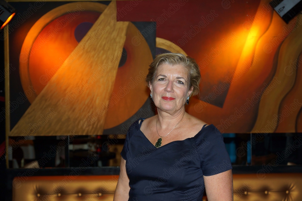 Portrait souriant d'une femme aux cheveux gris, en robe bleu marine.