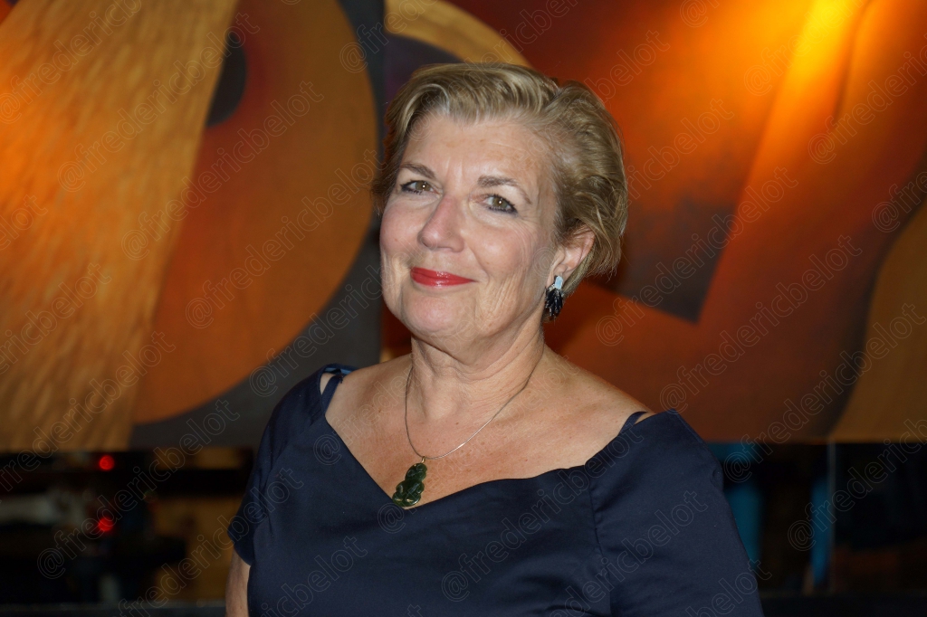 Portrait souriant d'une femme aux cheveux courts, en robe bleu marine.