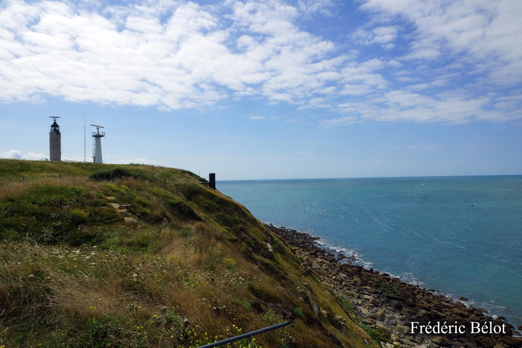Deux phares se dressent au sommet d'une falaise verdoyante surplombant la mer.