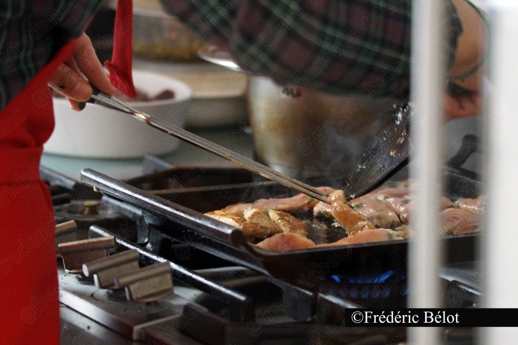Une personne fait griller de la viande sur un barbecue de rue.