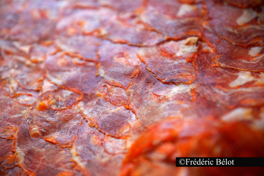 Des tranches de charcuterie séchée et épicée présentées en gros plan.