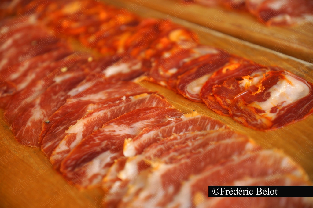 Des tranches de charcuterie épicée alignées sur une planche.