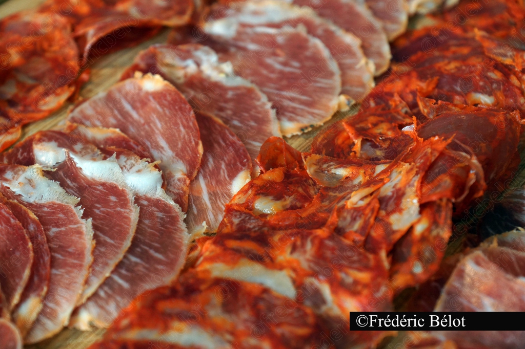 Des tranches de jambon cru disposées en éventail sur une planche.