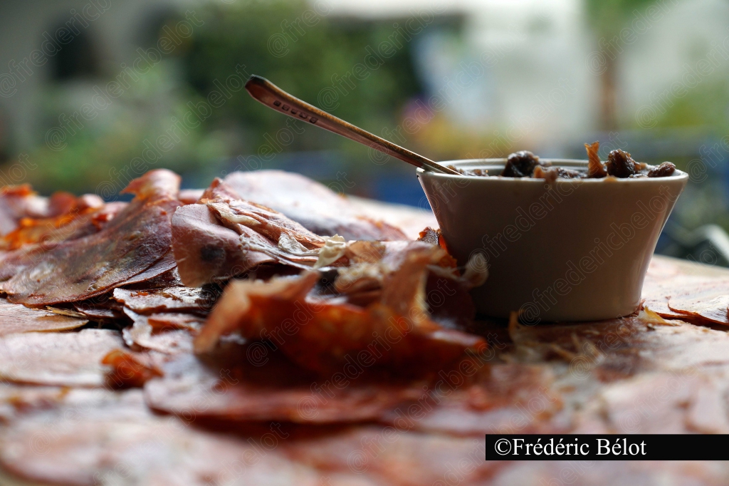 Des tranches de jambon cru disposées autour d'un bol de confiture, vue rapprochée.