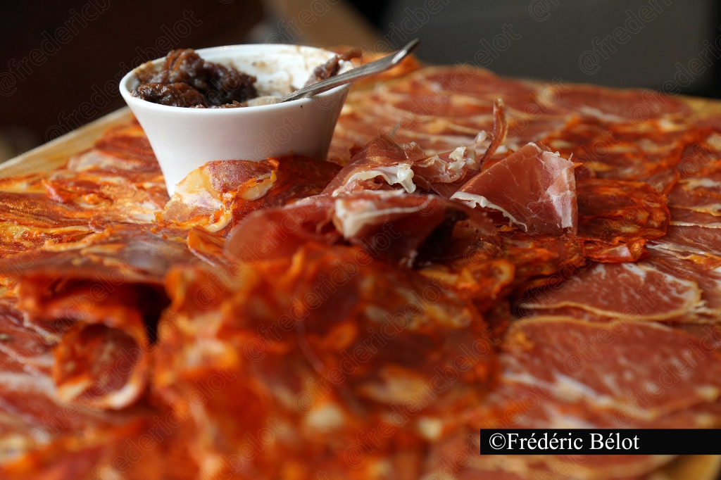 Un bol de confiture posé sur des tranches de jambon cru.