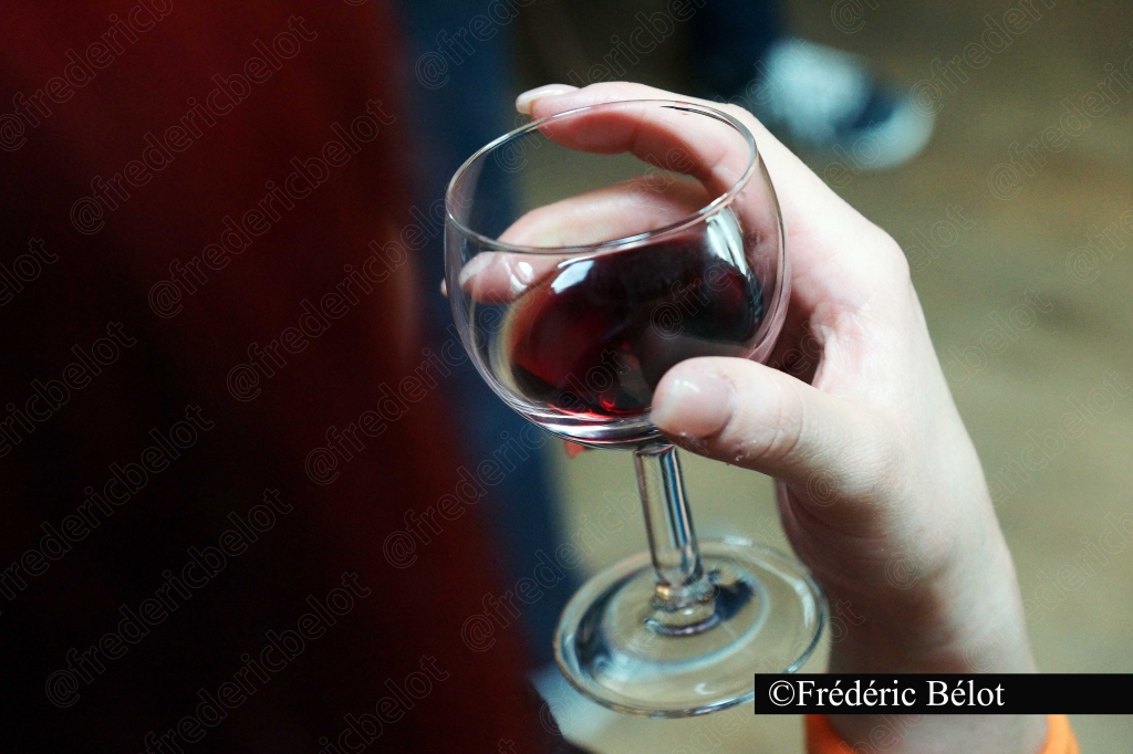 Une main tient un verre de vin rouge.