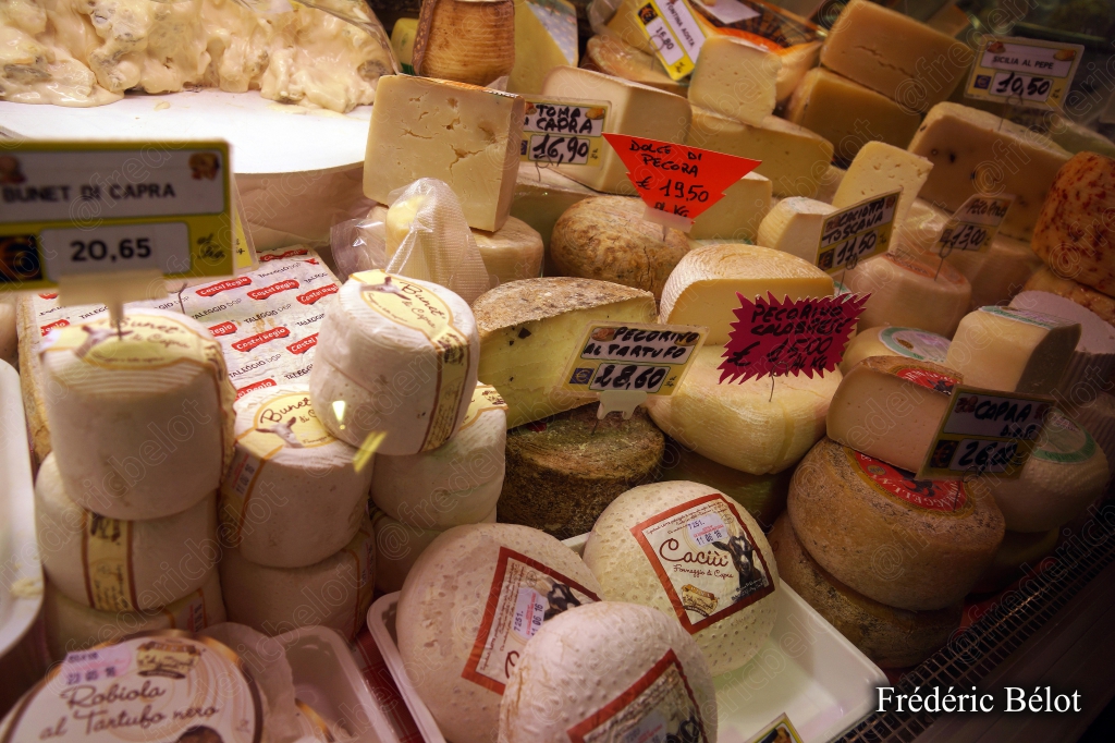 Un étal de fromages de chèvre variés, étiquettes de prix.