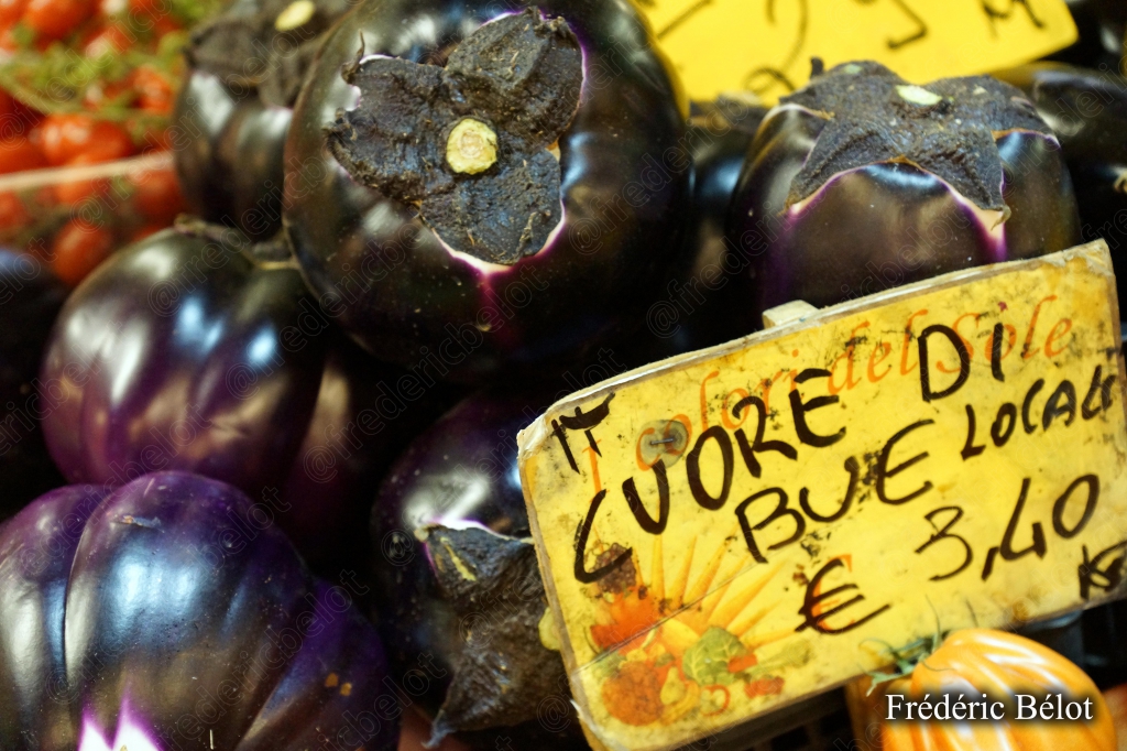 Des aubergines violettes présentées en tas, étiquette "Cuore di Bue".