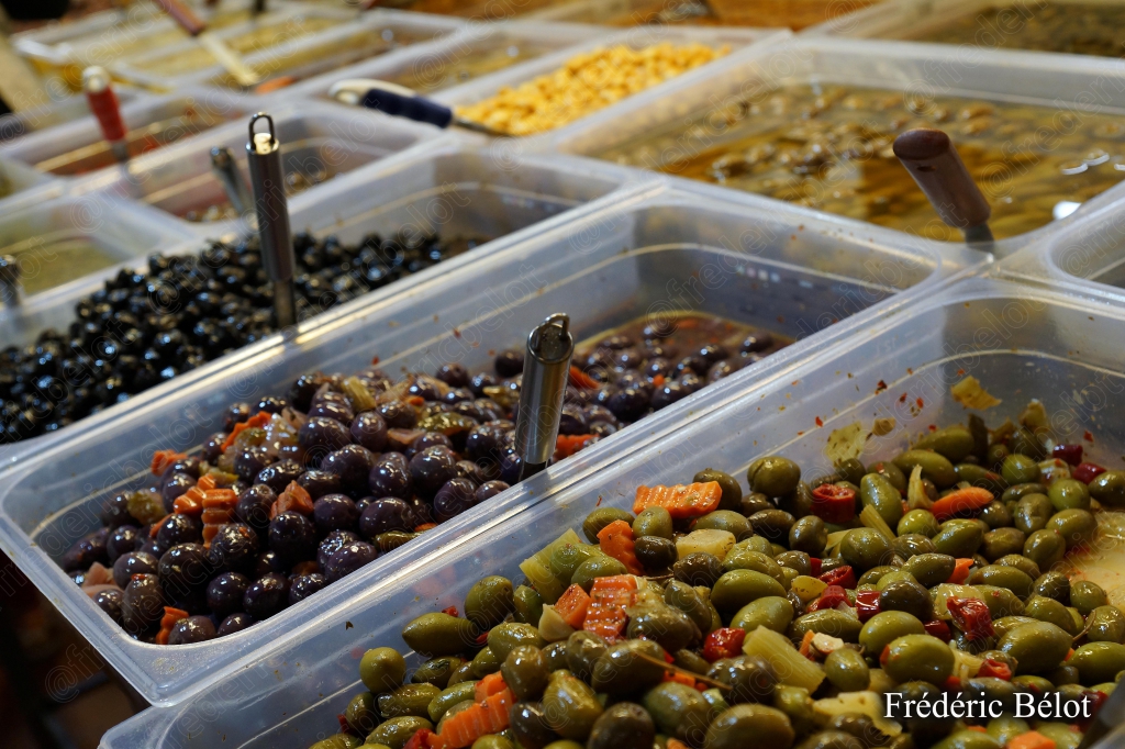 Un étal d'olives marinées variées présentées en bacs.