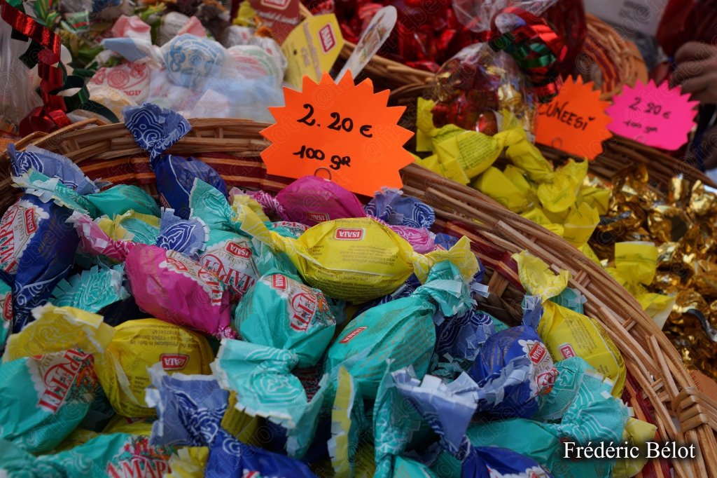 Des bonbons emballés colorés présentés en panier, étiquettes de prix.