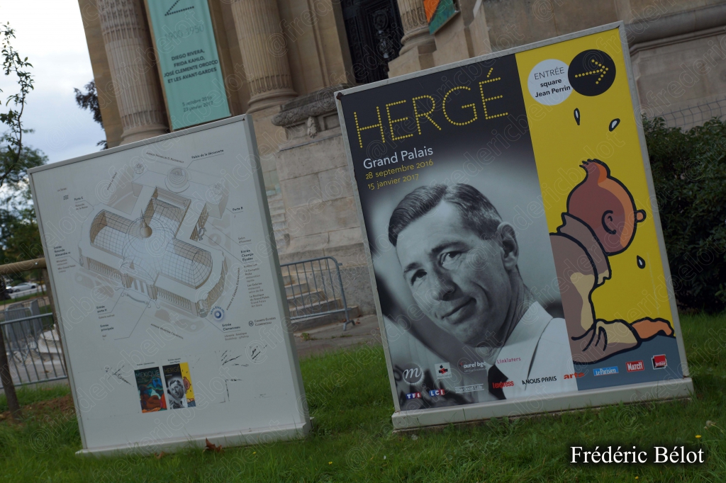 Un panneau d'exposition "Hergé, Grand Palais" à l'entrée, portrait du dessinateur et Tintin curieux.