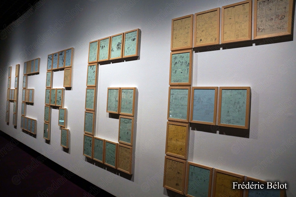 Le mot "HERGÉ" formé en grandes lettres par des vitrines encadrées sur un mur d'exposition.
