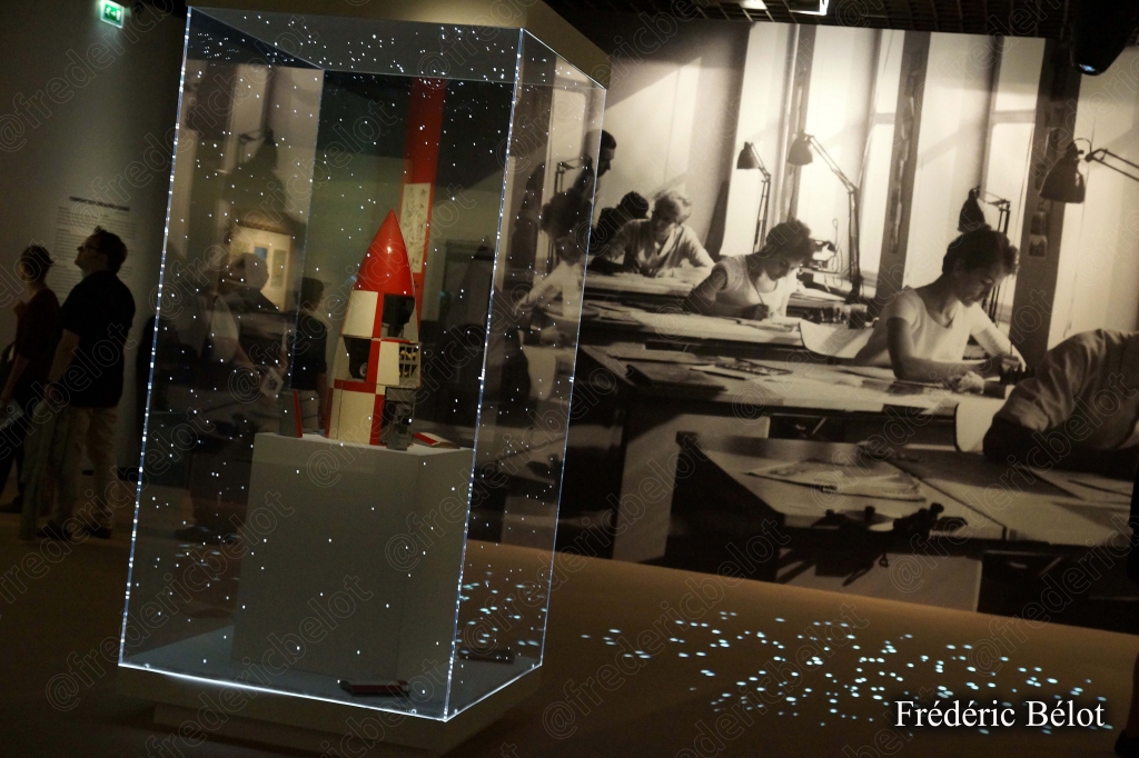Une vitrine d'exposition dans une salle sombre, éclairage tamisé sur les objets présentés.