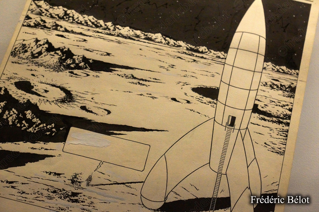 Une fusée-lune miniature exposée dans une salle plongée dans le noir, ambiance spatiale.