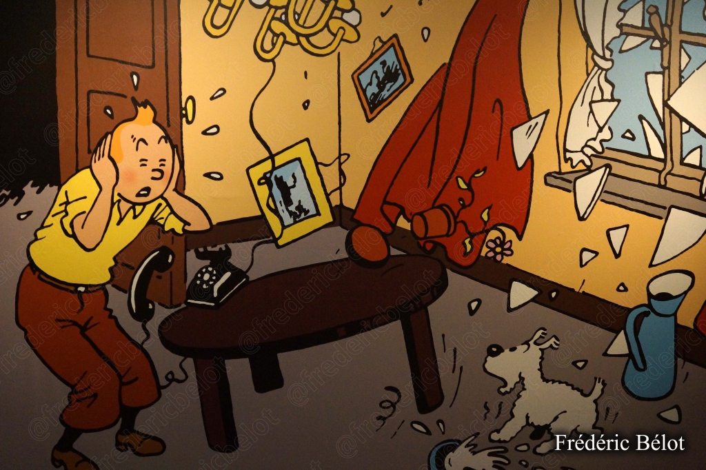 Une planche de bande dessinée représentant Tintin courant dans une rue en ruines après une explosion.