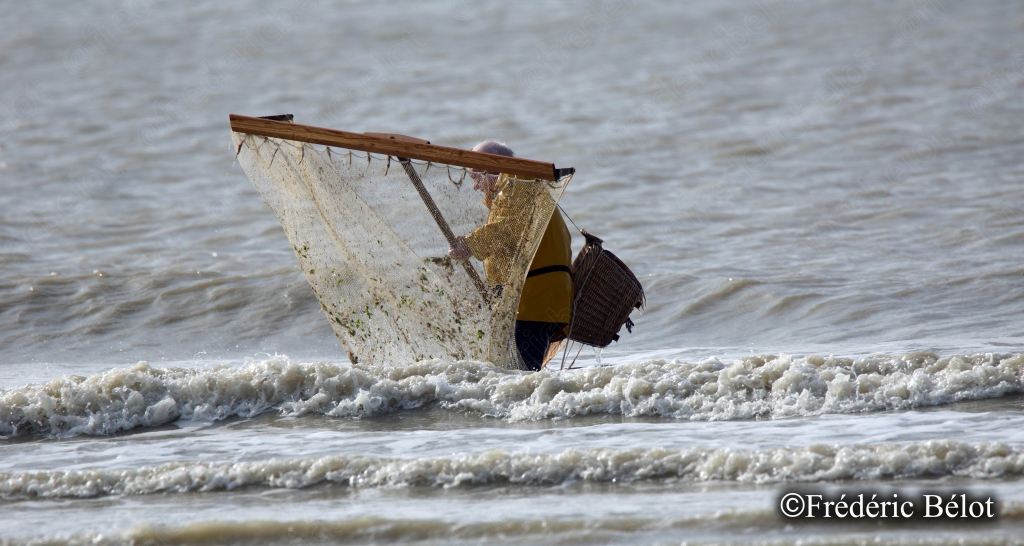 Un haveneau vide est posé face aux vagues, sur une plage embrumée.