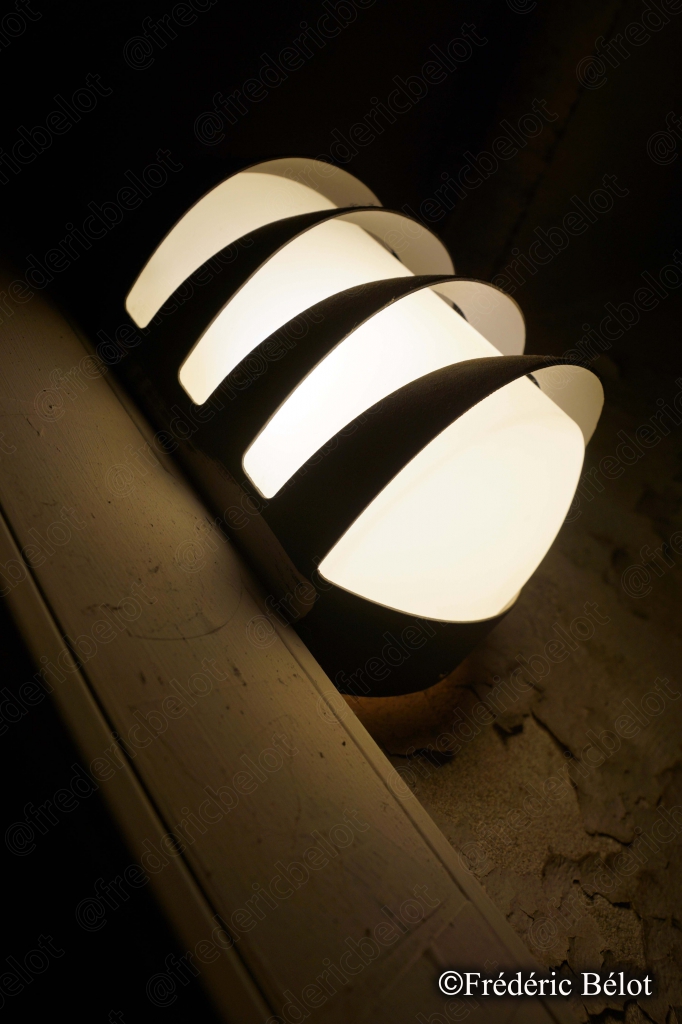 Une applique lumineuse moderne éclaire doucement un mur de la galerie souterraine.