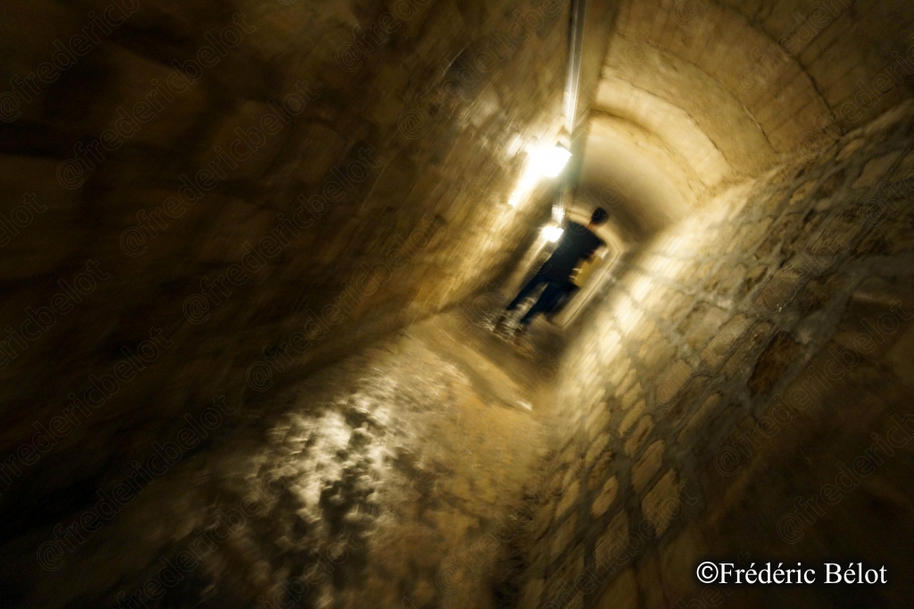 Une silhouette avance au bout d'un long tunnel éclairé en enfilade.