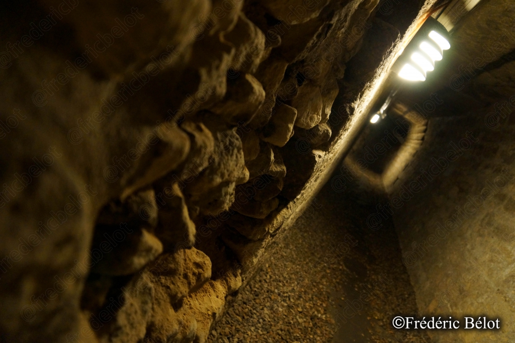 Un couloir étroit taillé dans la roche, éclairé par une lumière chaude.