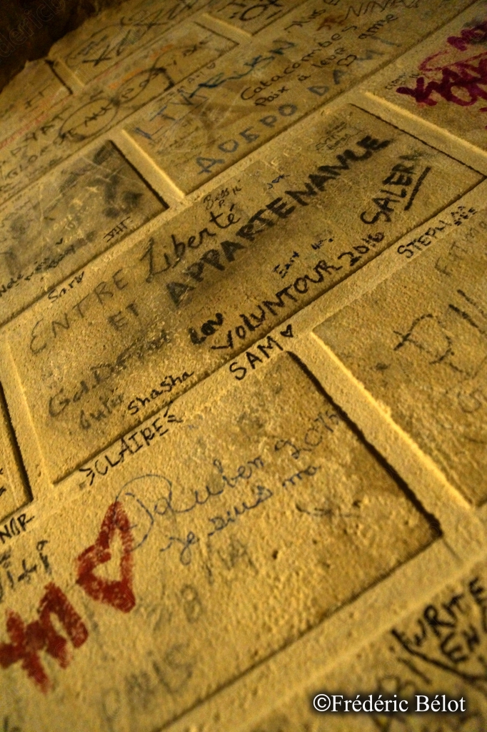 Un mur de pierre couvert d'inscriptions et de signatures laissées par des visiteurs.