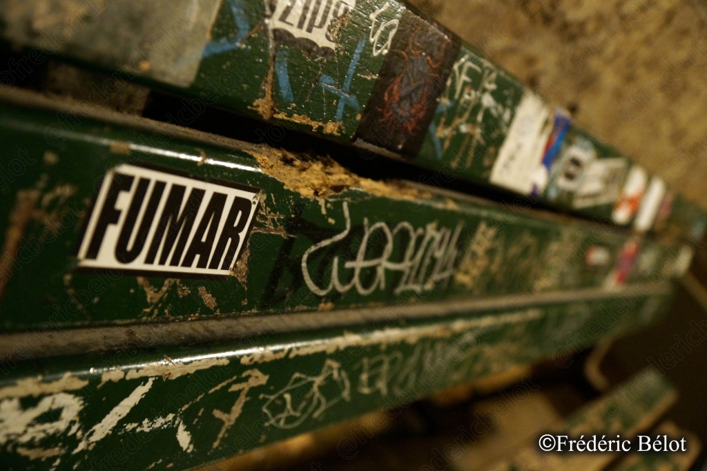 Une ancienne poutre métallique verte couverte d'autocollants et de graffitis.